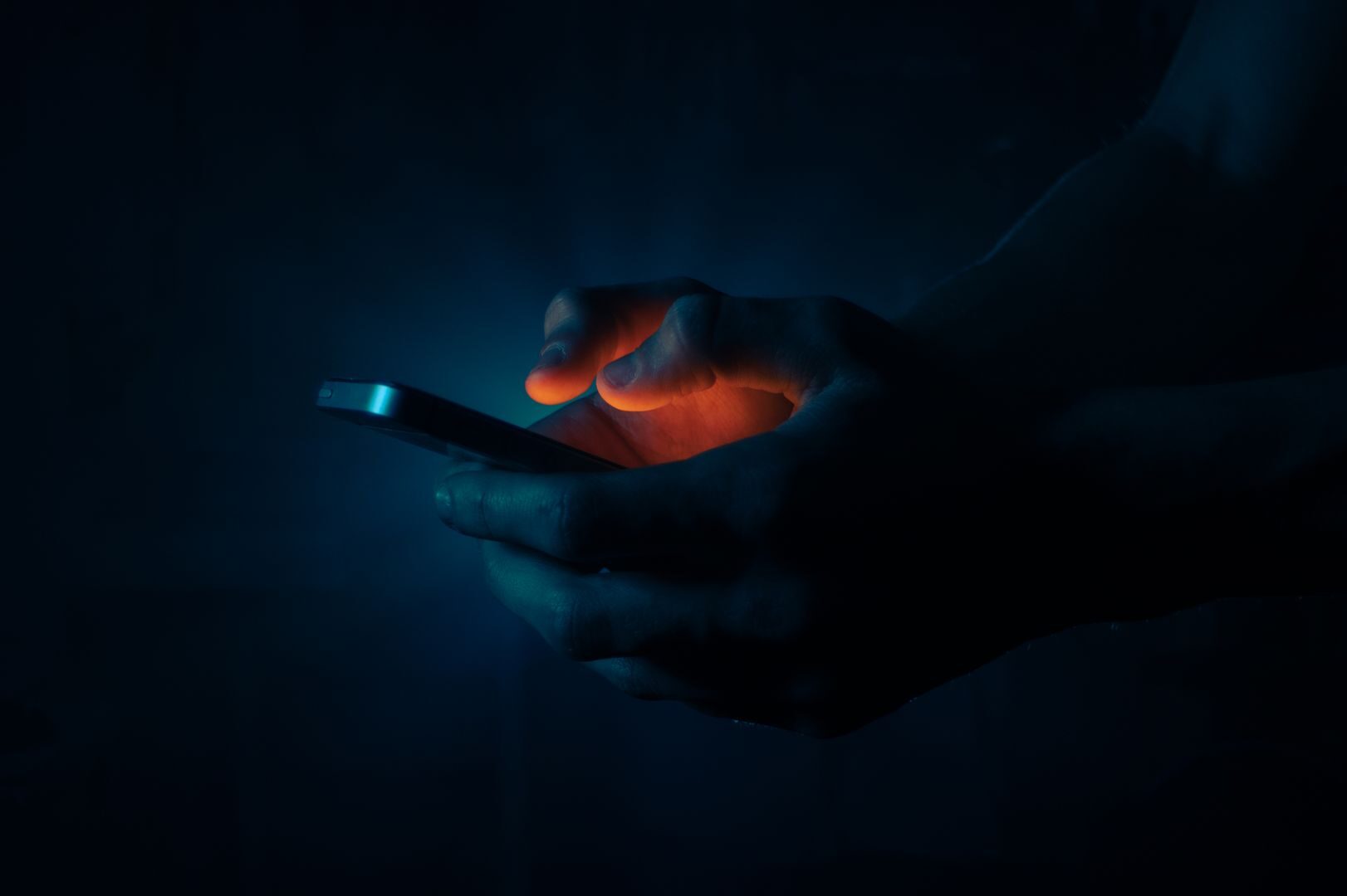 Person using a laptop in a dimly lit office, illustrating shadow AI usage